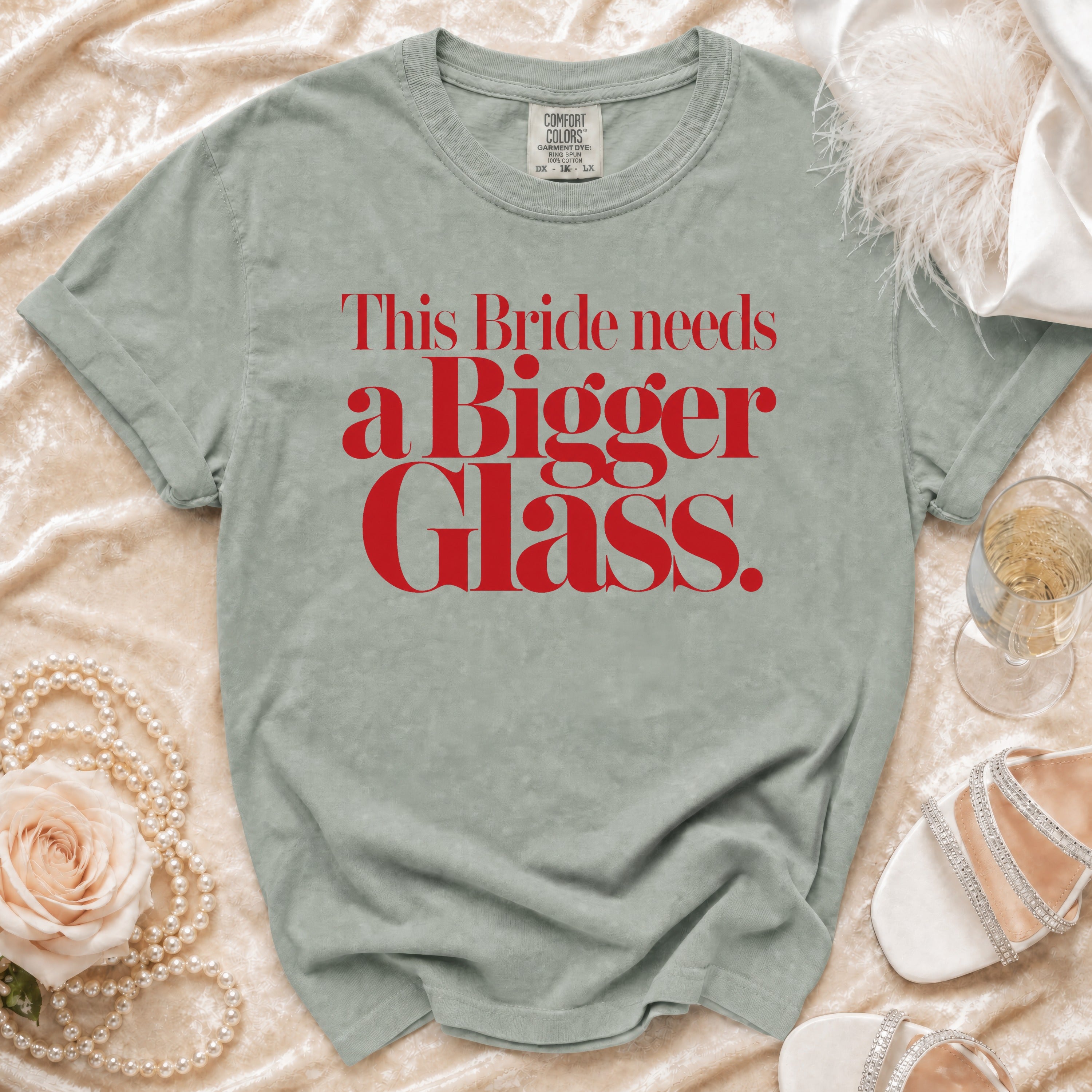 Light green Comfort Colors t-shirt with red text that reads "This Bride needs a Bigger Glass."