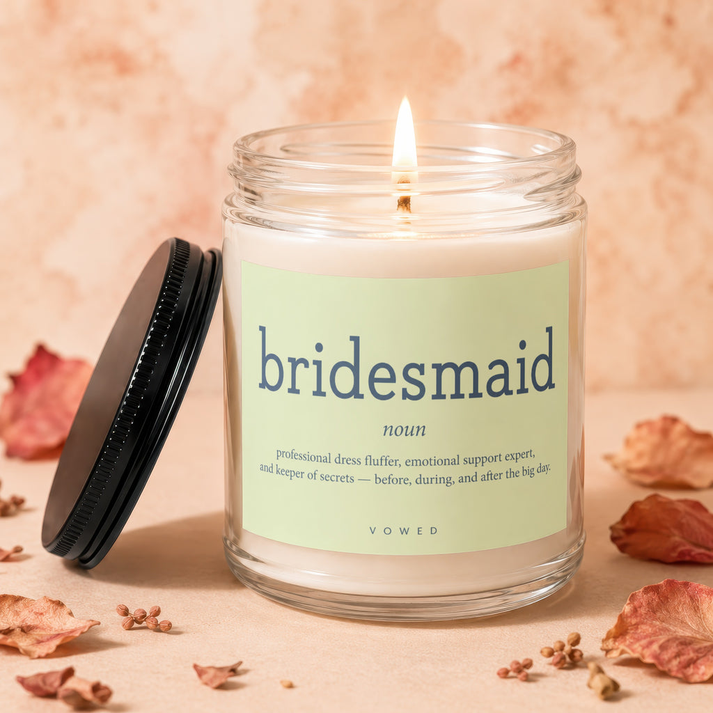 Lit candle with "bridesmaid" definition label and surrounding dried floral elements.