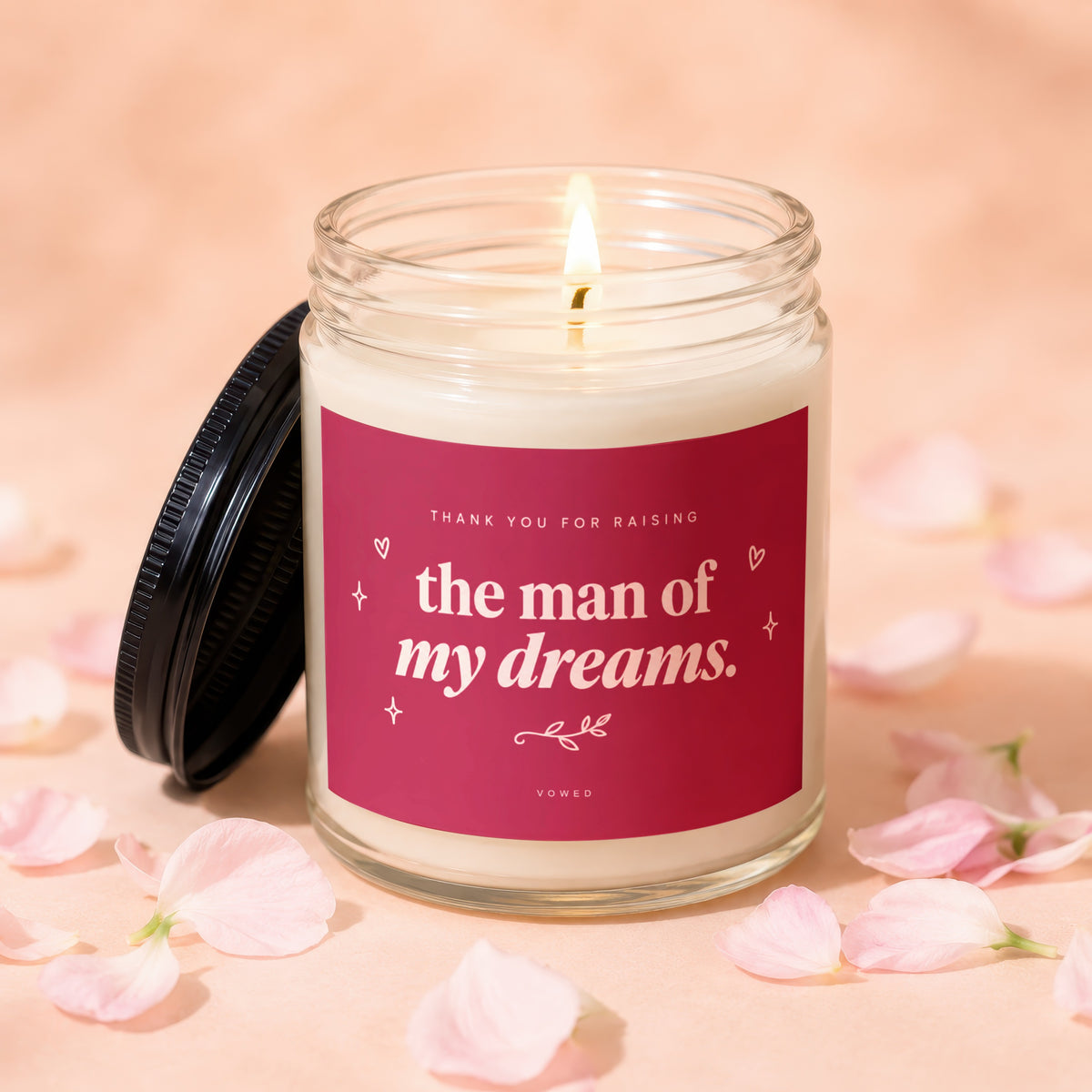 Glass candle with burning wick, pink label reads "the man of my dreams."
