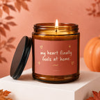 Amber candle with lit wick and "my heart finally feels at home." text.