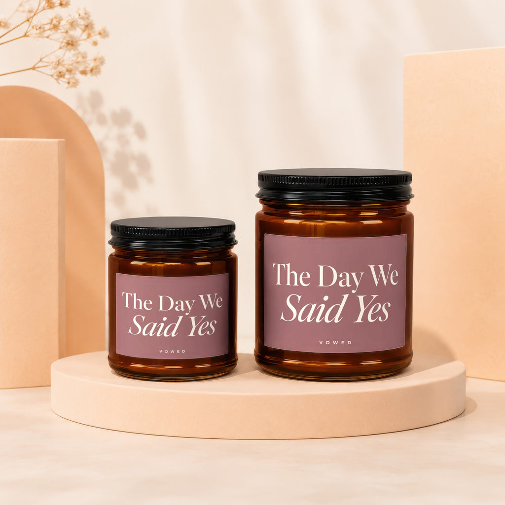Two amber glass candles with black lids read "The Day We Said Yes".