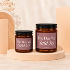 Two amber glass candles with black lids read "The Day We Said Yes".