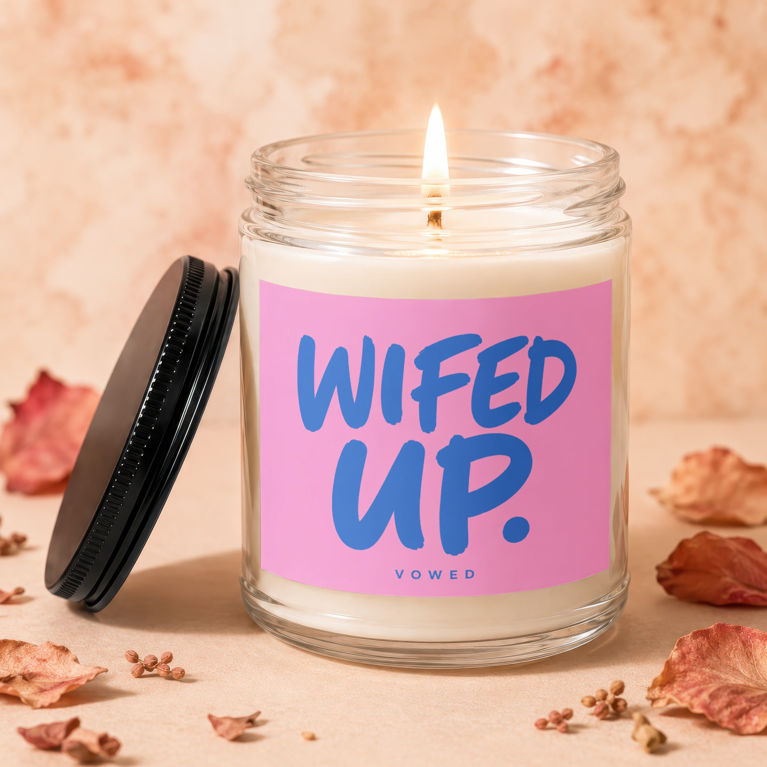 Candle with "WIFED UP." and "VOWED" text on a pink label.