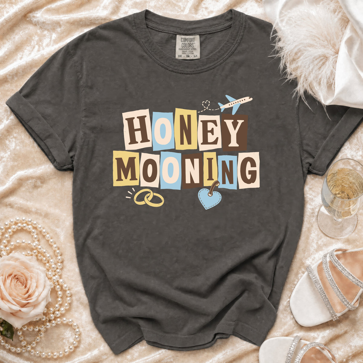 Dark grey t-shirt with "HONEY MOONING" text and travel icons.