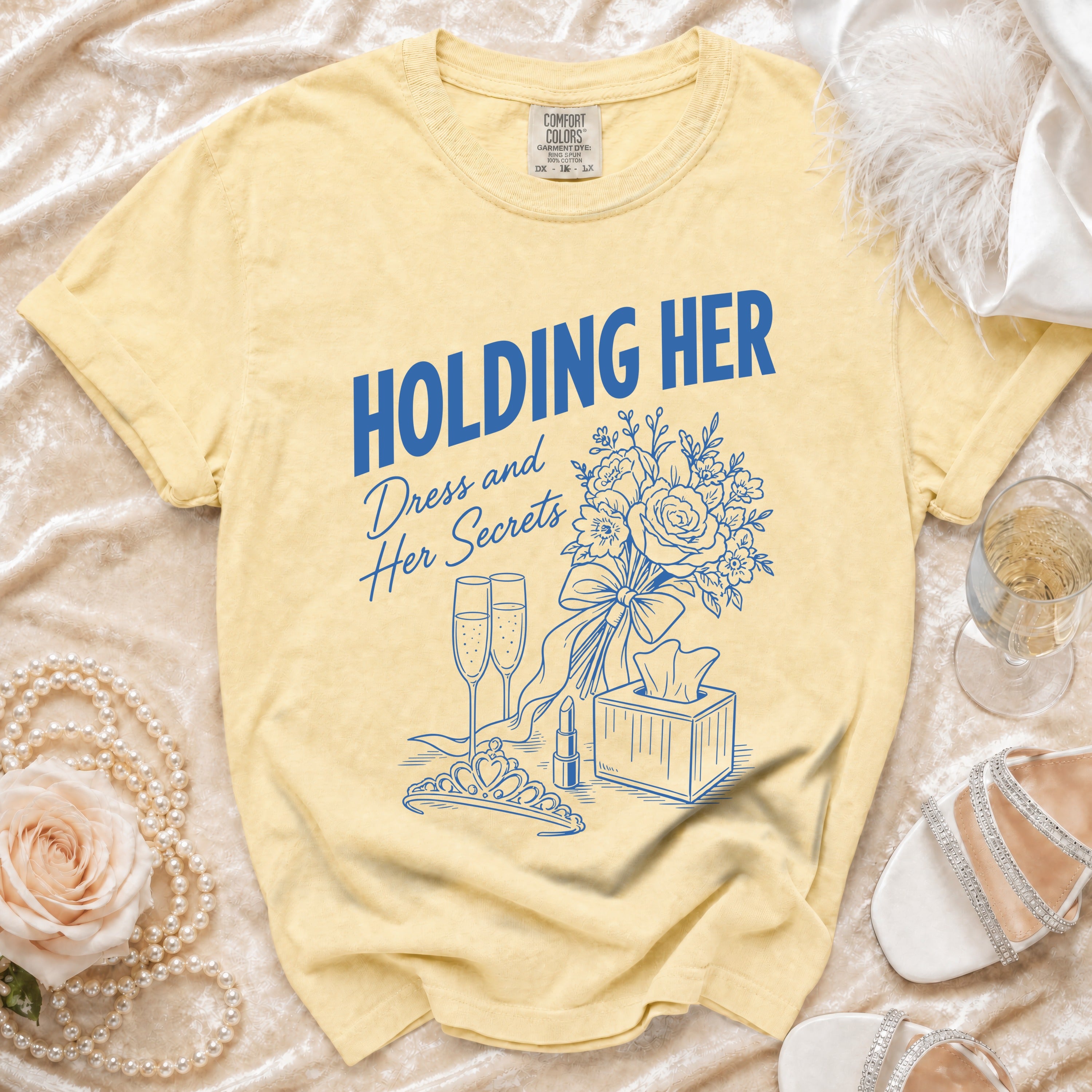 Yellow t-shirt with blue text "Holding Her Dress and Her Secrets" and floral graphic.