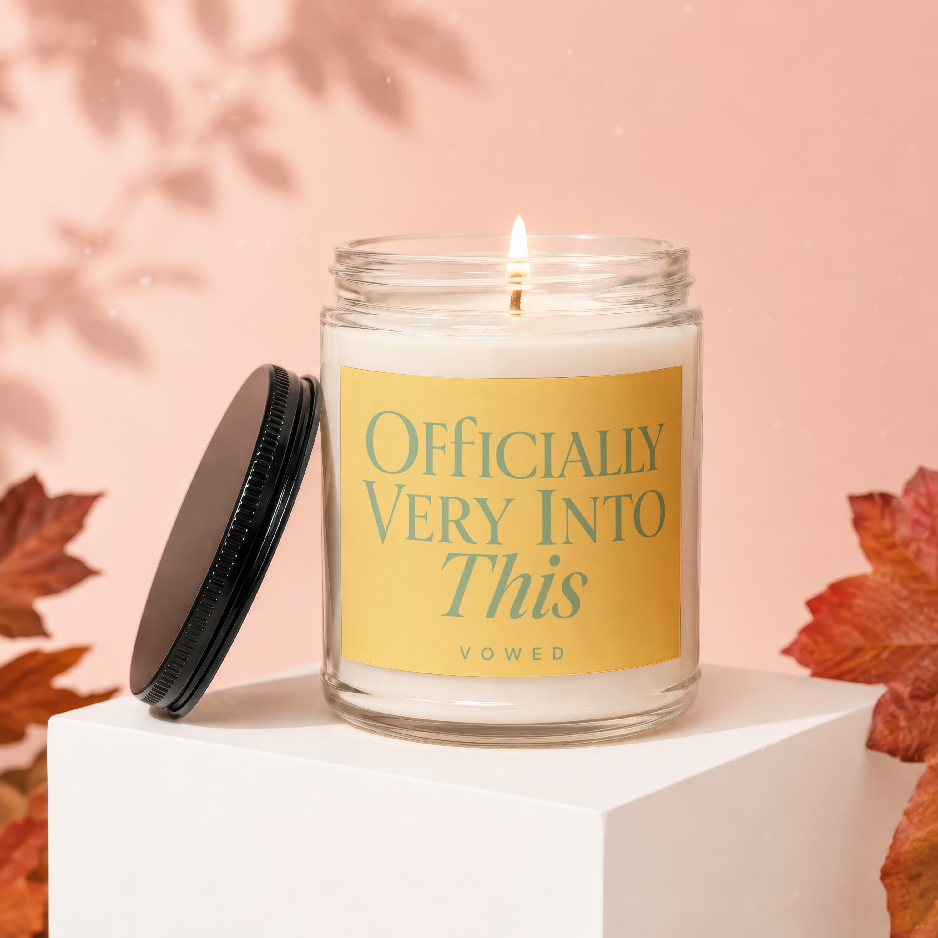 Glass jar candle with yellow label reading "Officially Very Into This" and "vowed".