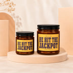 Two amber glass candles with yellow labels reading "HE HIT THE JACKPOT".