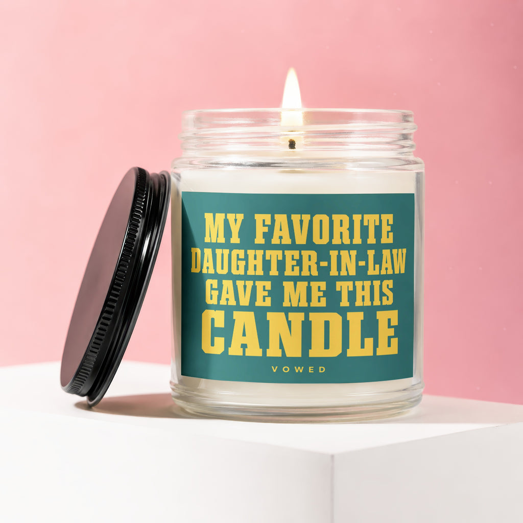 Glass candle with lit wick and black lid, labeled "My Favorite Daughter-In-Law Gave Me This Candle."