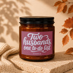 Brown glass candle with pink label reading "Two husbands, one to-do list".