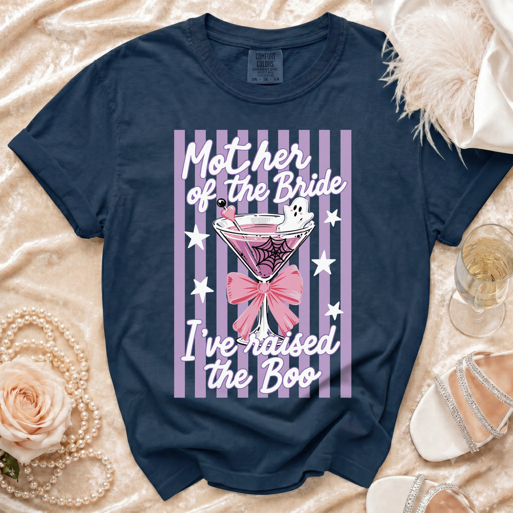 A navy blue t-shirt with a pink-striped graphic featuring a martini glass, ghost, and the text Mother of the Bride I've raised the Boo.