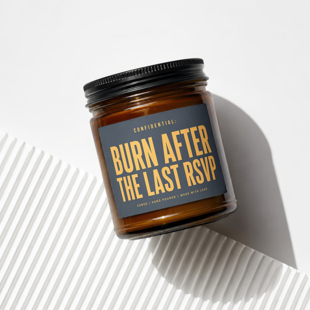 Amber jar candle with dark gray label that reads "CONFIDENTIAL: BURN AFTER THE LAST RSVP".