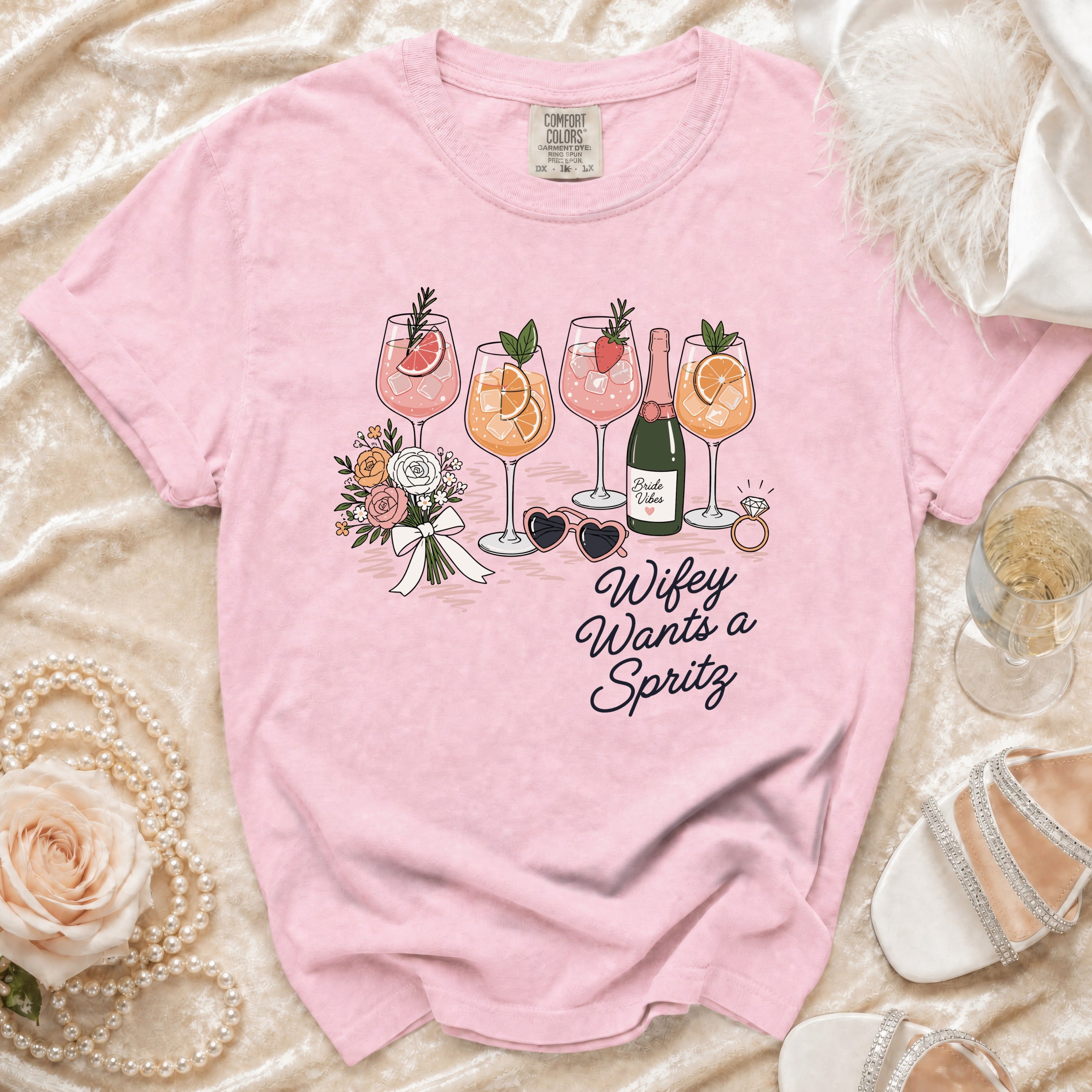 Pink t-shirt with graphic of cocktails, flowers, and text "Wifey Wants a Spritz".