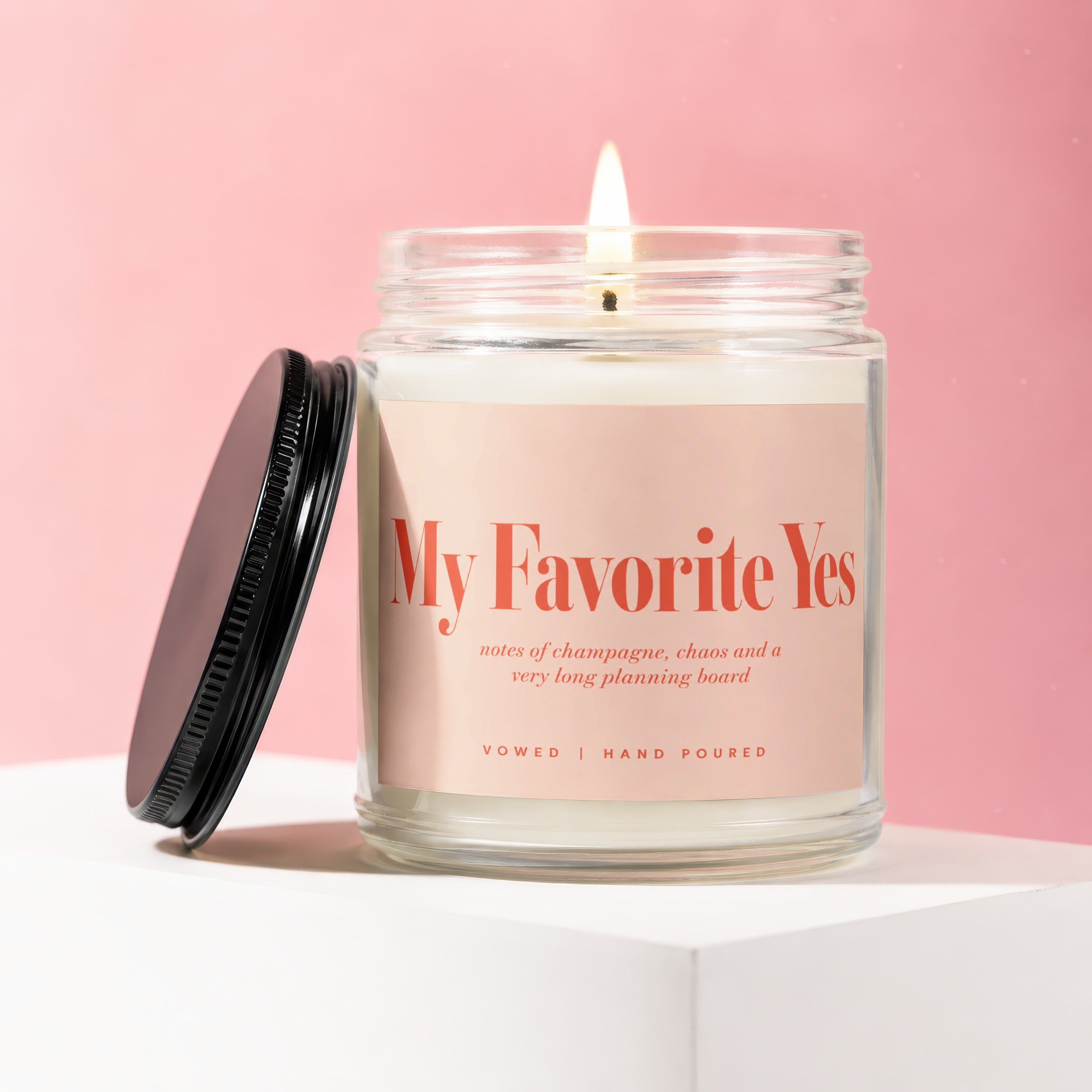 Lit candle with "My Favorite Yes" label and scent notes "notes of champagne, chaos and a very long planning board".