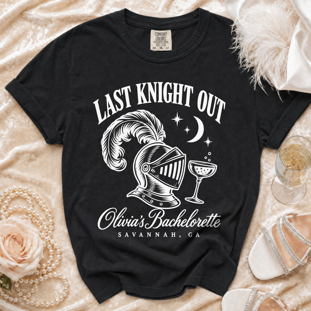 Black Comfort Colors t-shirt featuring white text that reads Last Knight Out above a plumed knight helmet, a champagne glass, a crescent moon, and the text Olivia's Bachelorette Savannah, GA.