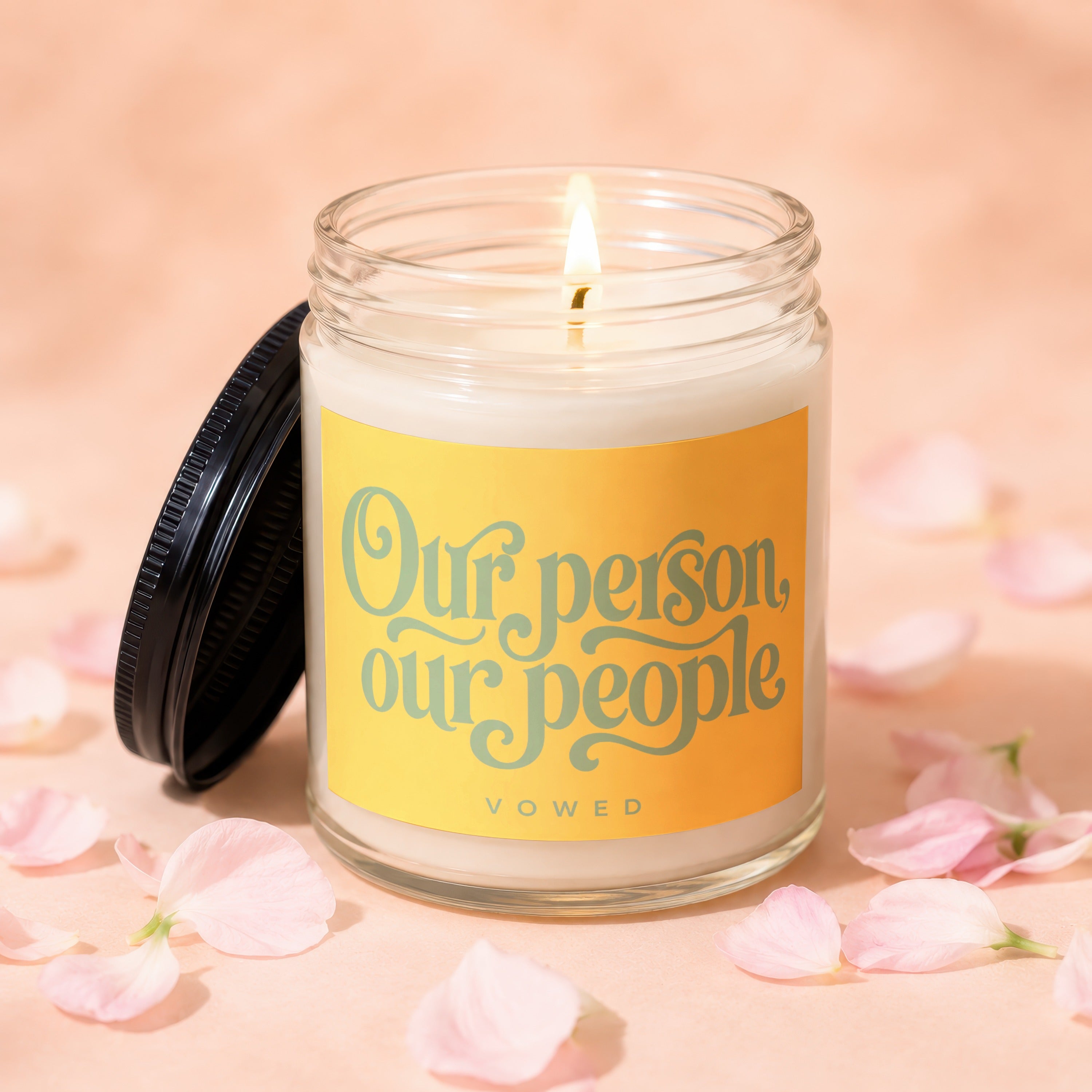 Candle with a lit wick and a yellow label reading "Our person, our people VOWED".
