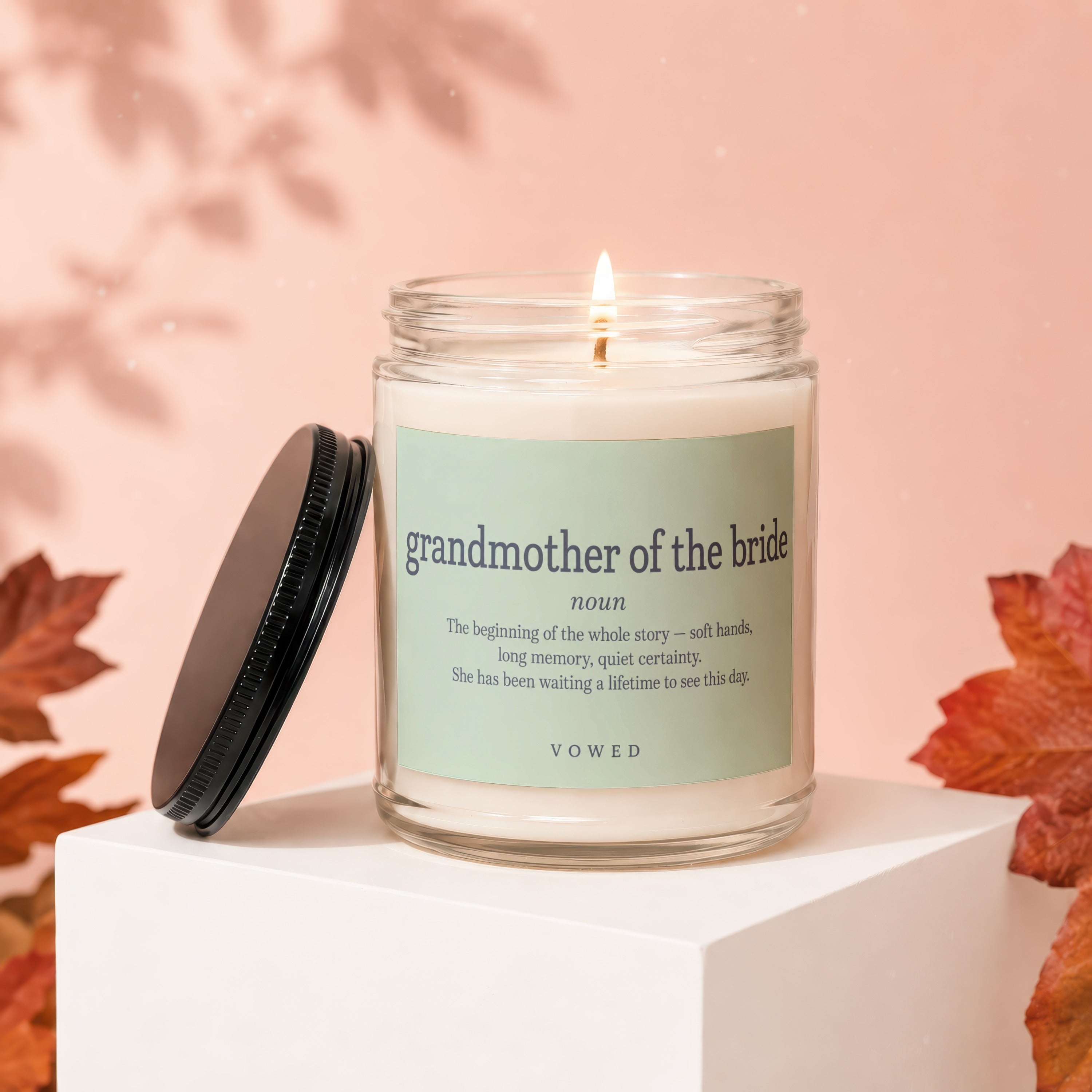 Lit candle for "grandmother of the bride" with definition and brand name on label.