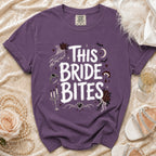 Purple t-shirt with "This Bride Bites" text and gothic wedding graphics.