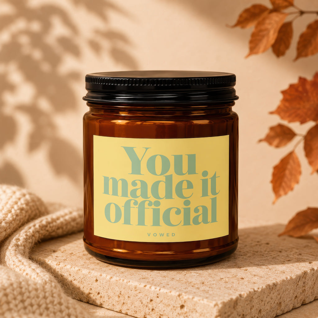 Amber jar candle with yellow label reading "You. made it official" with "VOWED" below.