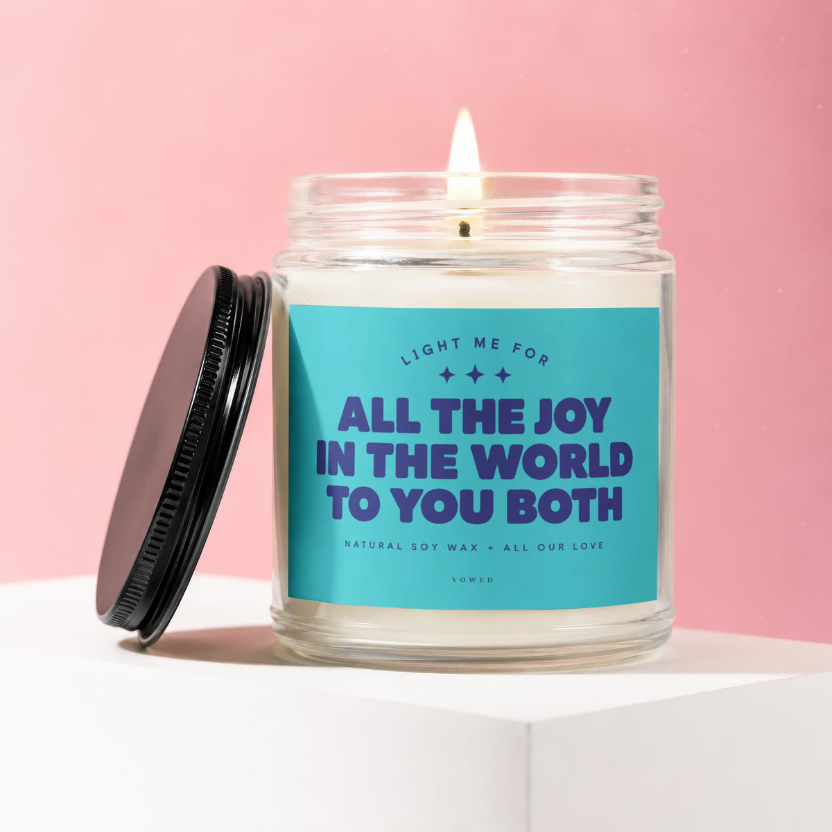 Glass candle with lid off, reading "Light me for all the joy in the world to you both".