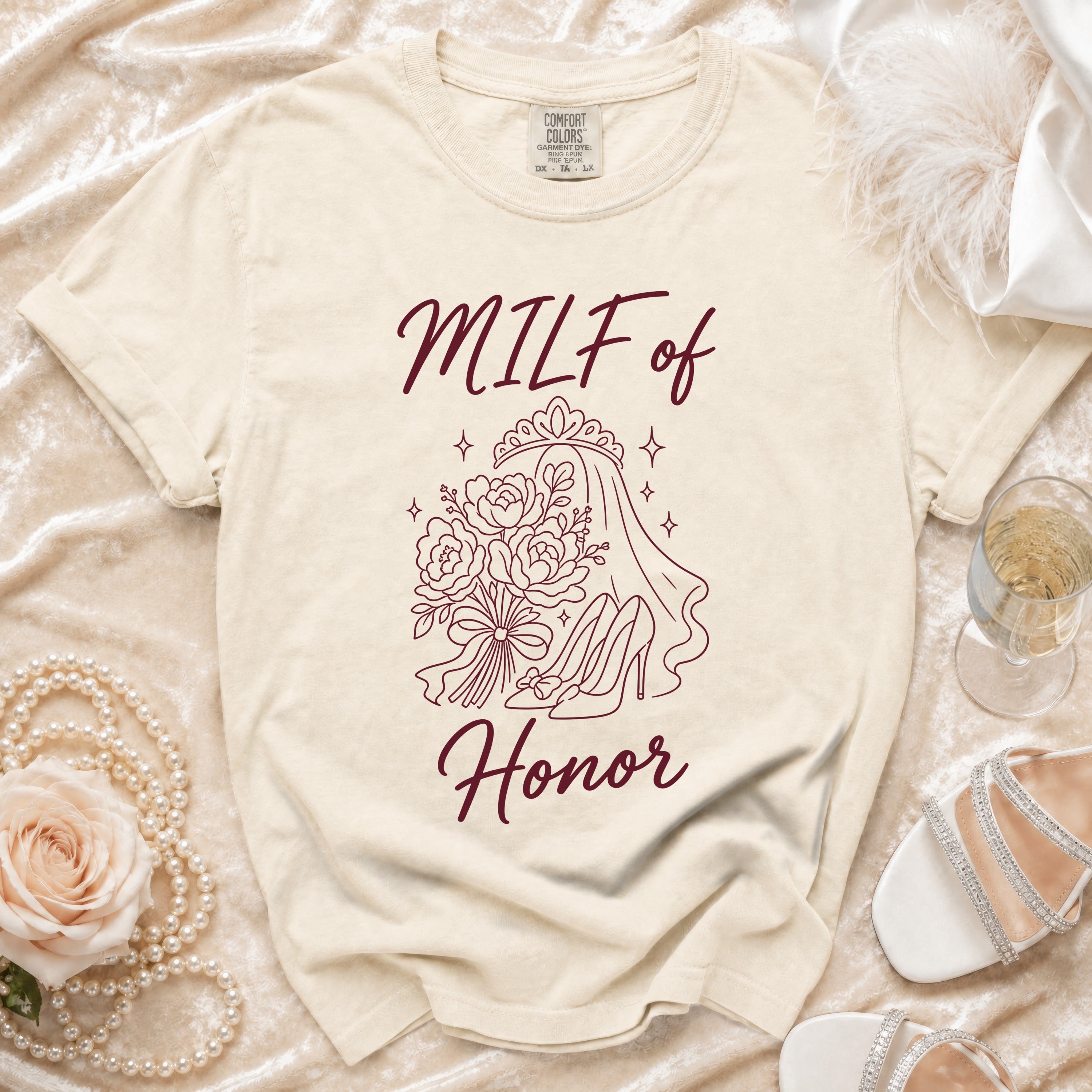 Cream t-shirt with "MILF of Honor" text and outline graphic of a bouquet, tiara, and heels.