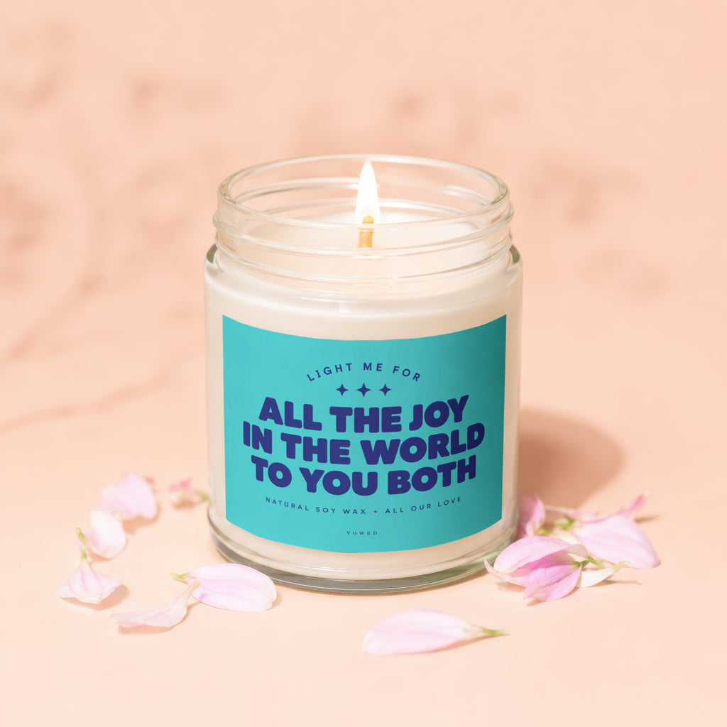 Candle with text "All the joy in the world to you both," surrounded by petals.