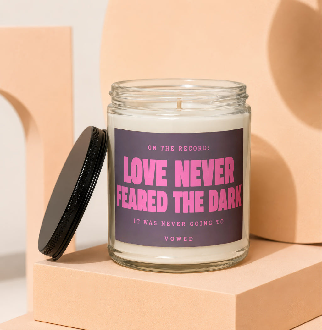 Glass candle with black lid, featuring text "Love Never Feared The Dark".