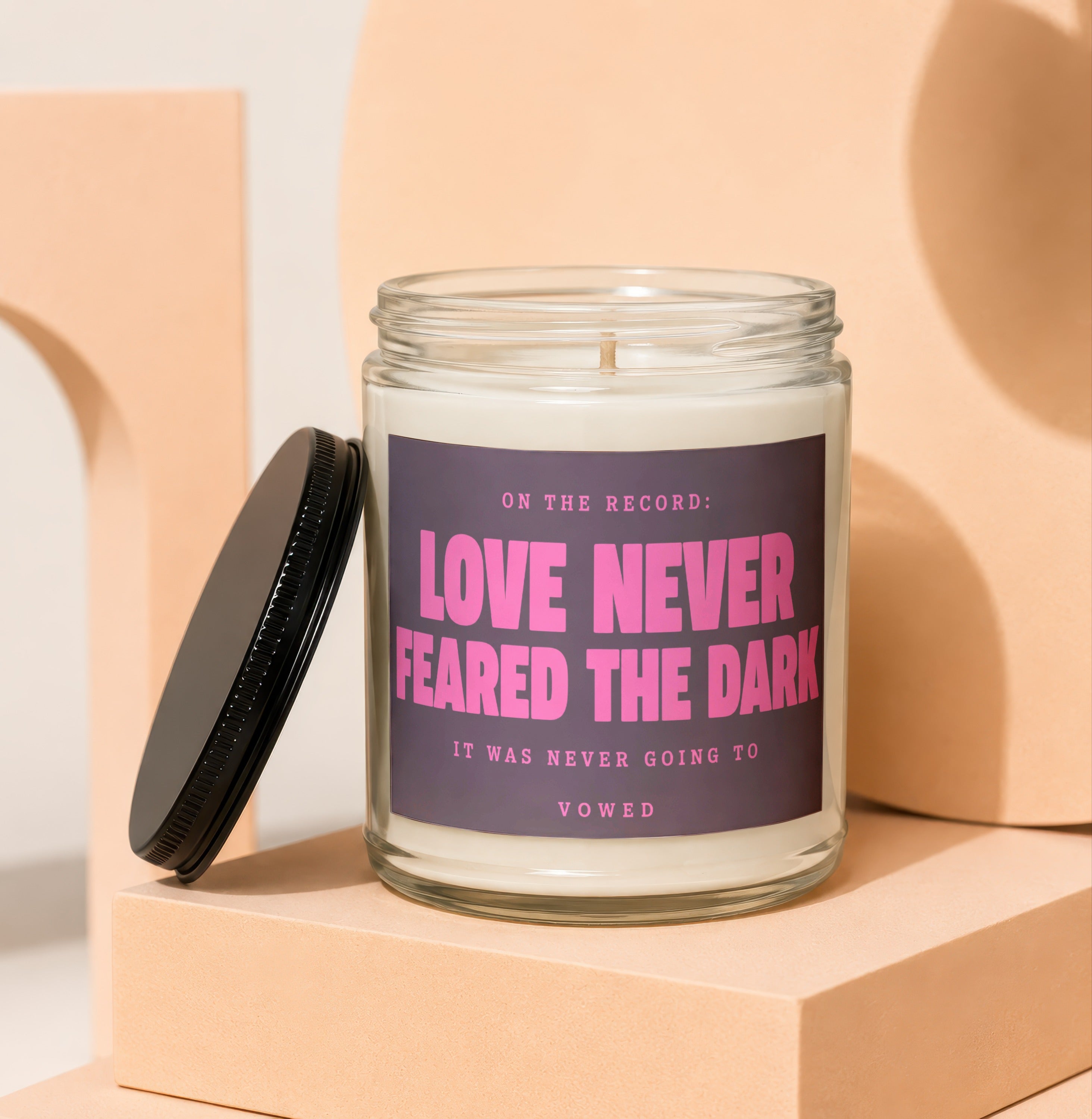 Glass candle with black lid, featuring text "Love Never Feared The Dark".