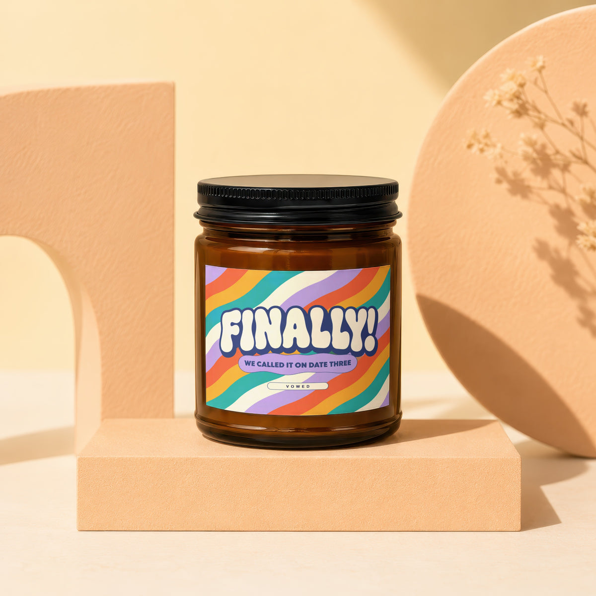Brown candle with colorful label that reads "FINALLY! WE CALLED IT ON DATE THREE VOWED."