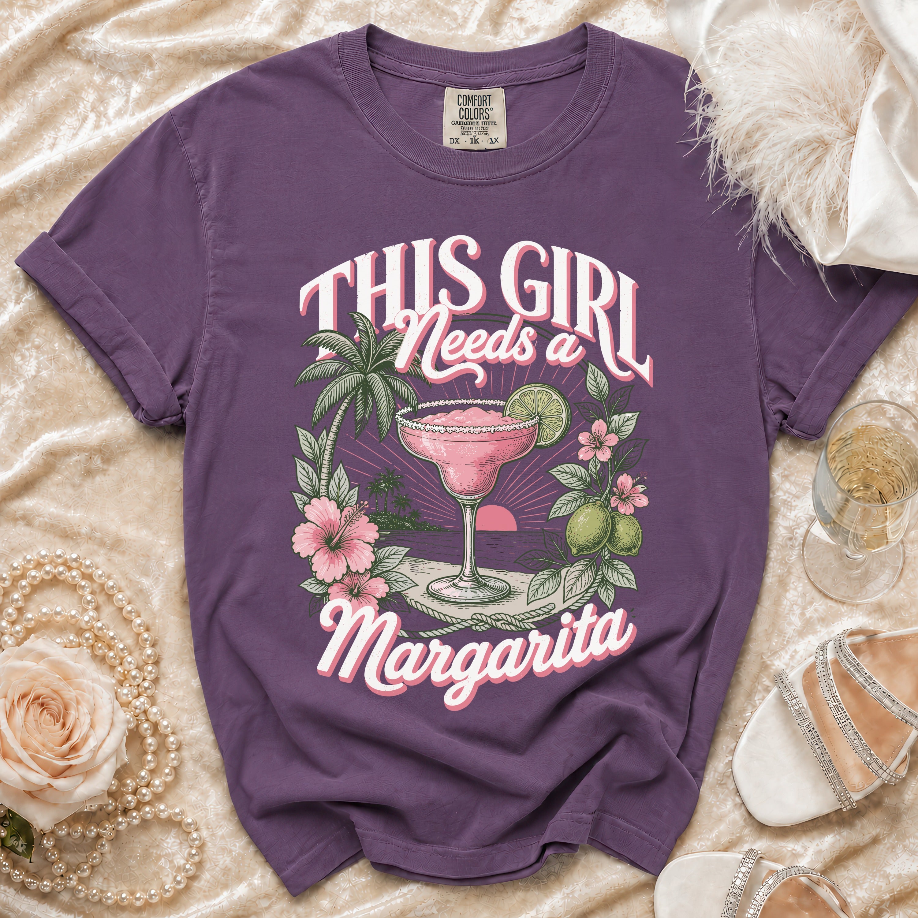 Purple t-shirt graphic with text "This Girl Needs a Margarita" and tropical drink.
