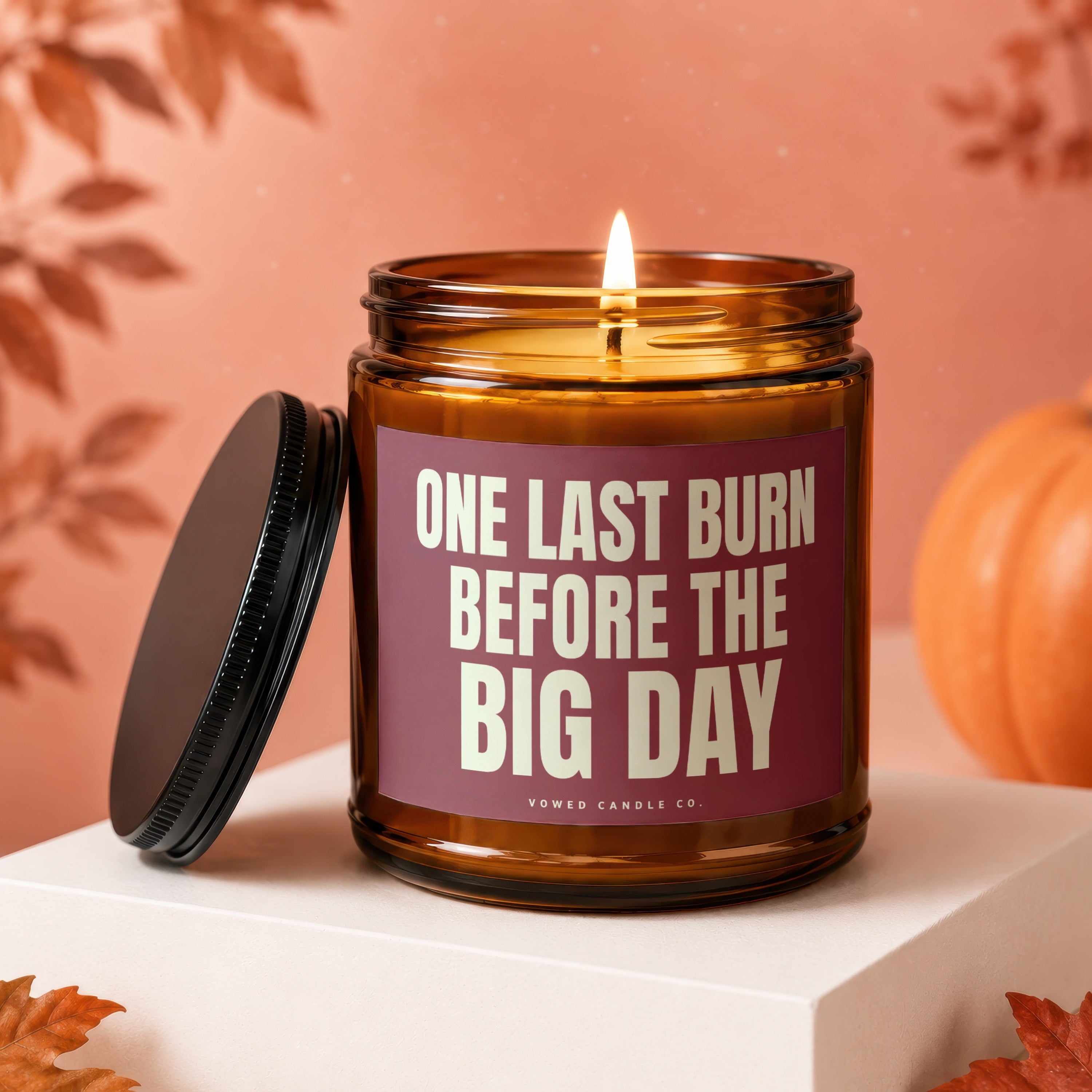 Amber jar candle with lit wick, maroon label reading "ONE LAST BURN BEFORE THE BIG DAY".