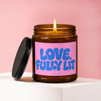 Amber jar candle with lit wick and black lid, text reads "LOVE, FULLY LIT".