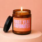 Lit amber glass candle with orange label reading "Year One: First Year Favorites."