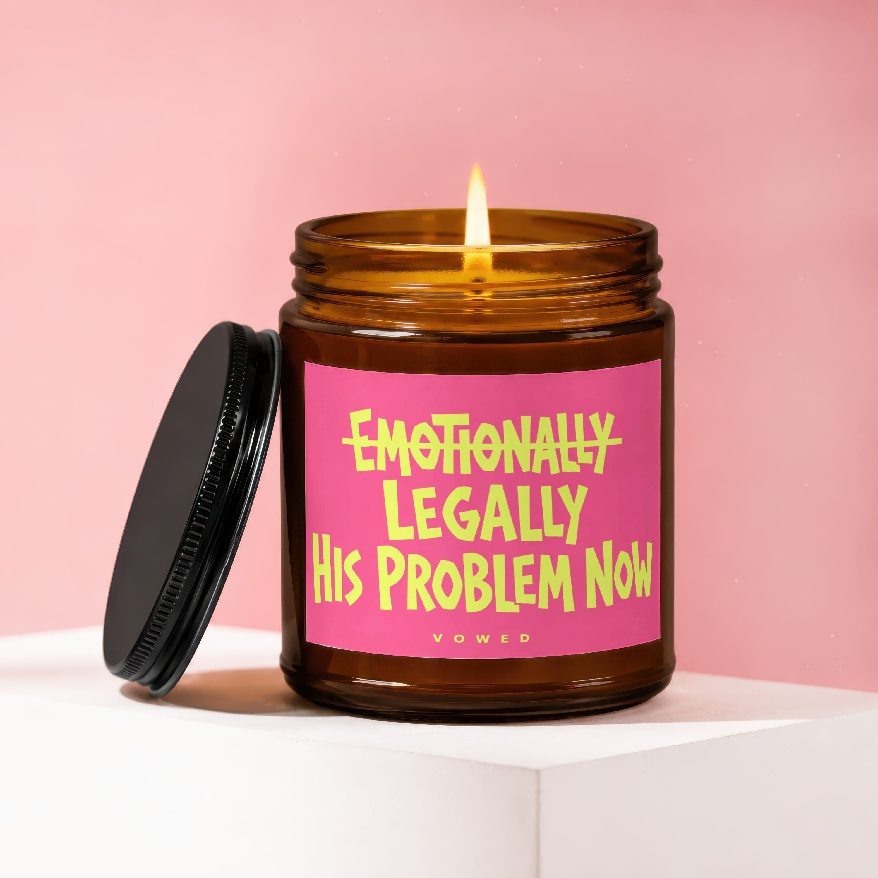 Amber candle with pink label reading "Emotionally Legally His Problem Now".