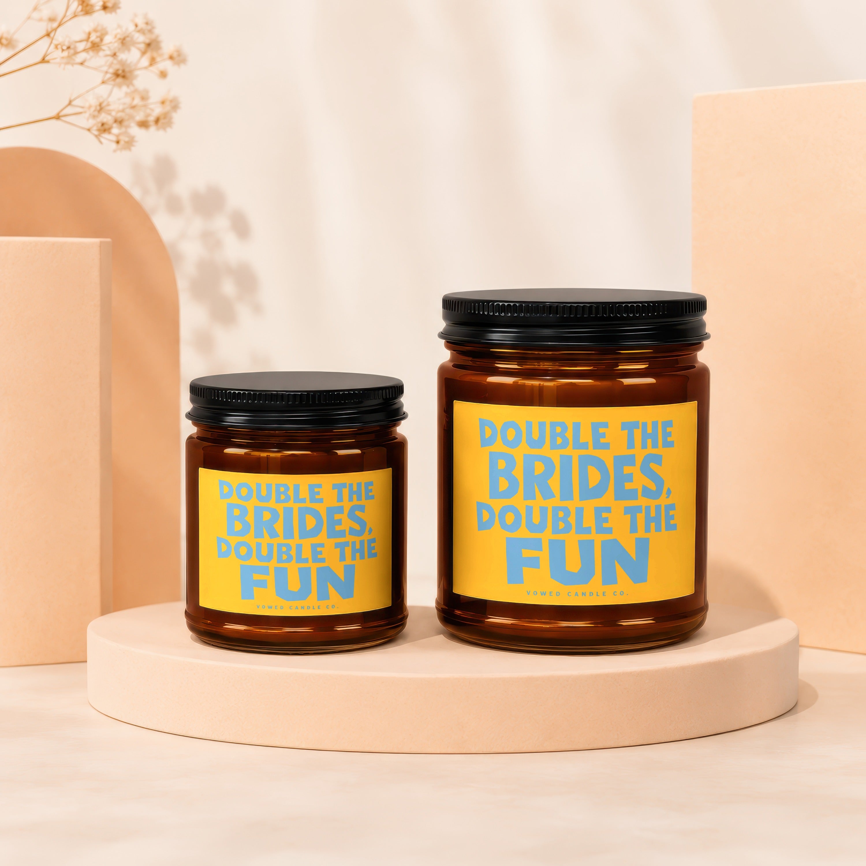 Two amber glass candles with yellow labels reading "Double the Brides, Double the Fun".