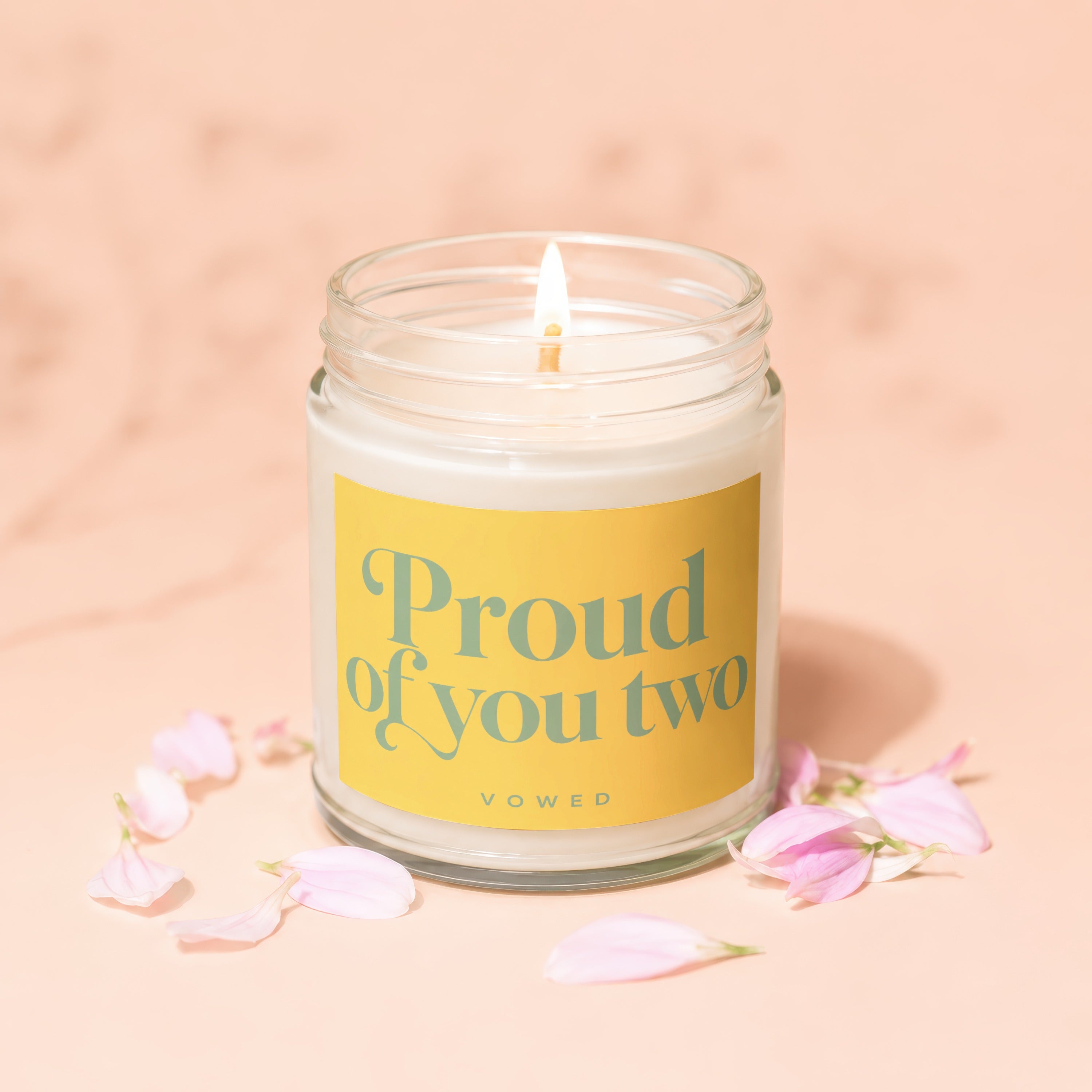 Glass jar candle with yellow label reading "Proud of you two" and "VOWED".