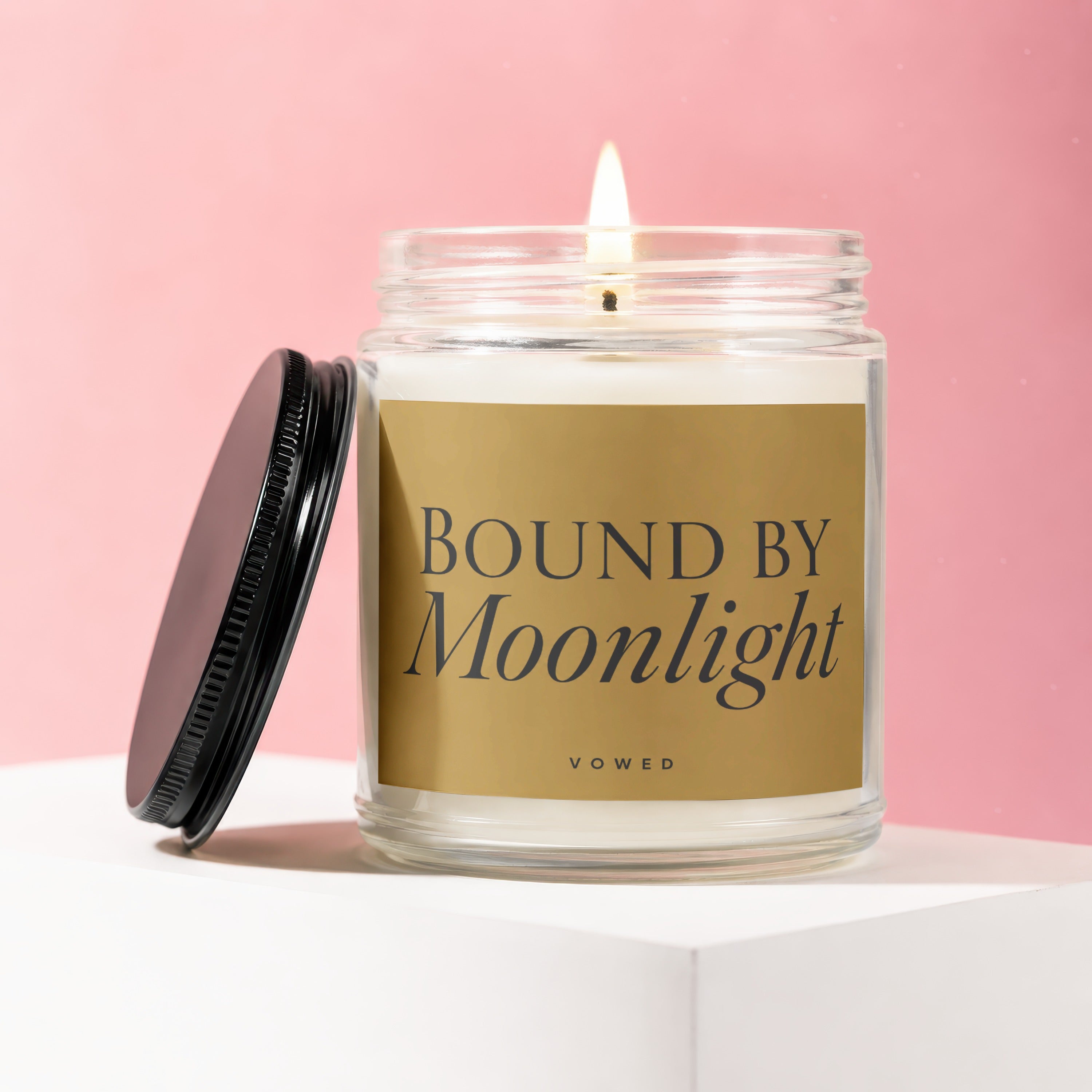 Candle labeled "BOUND BY Moonlight" with a lit wick on a white pedestal.