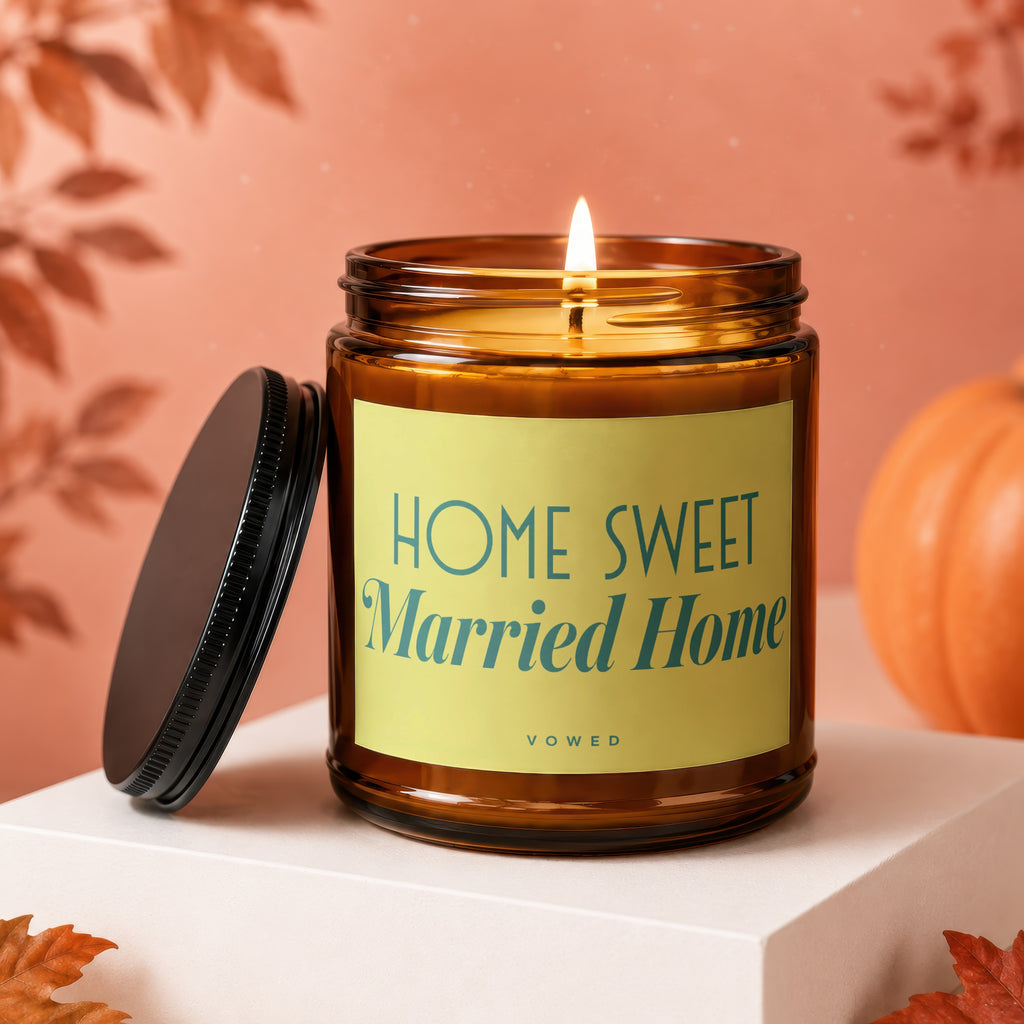 Amber jar candle with lit flame, "Home Sweet Married Home" text on label.