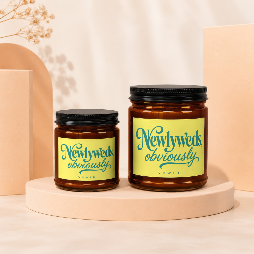 Two amber glass candles with black lids labeled "Newlyweds, obviously"