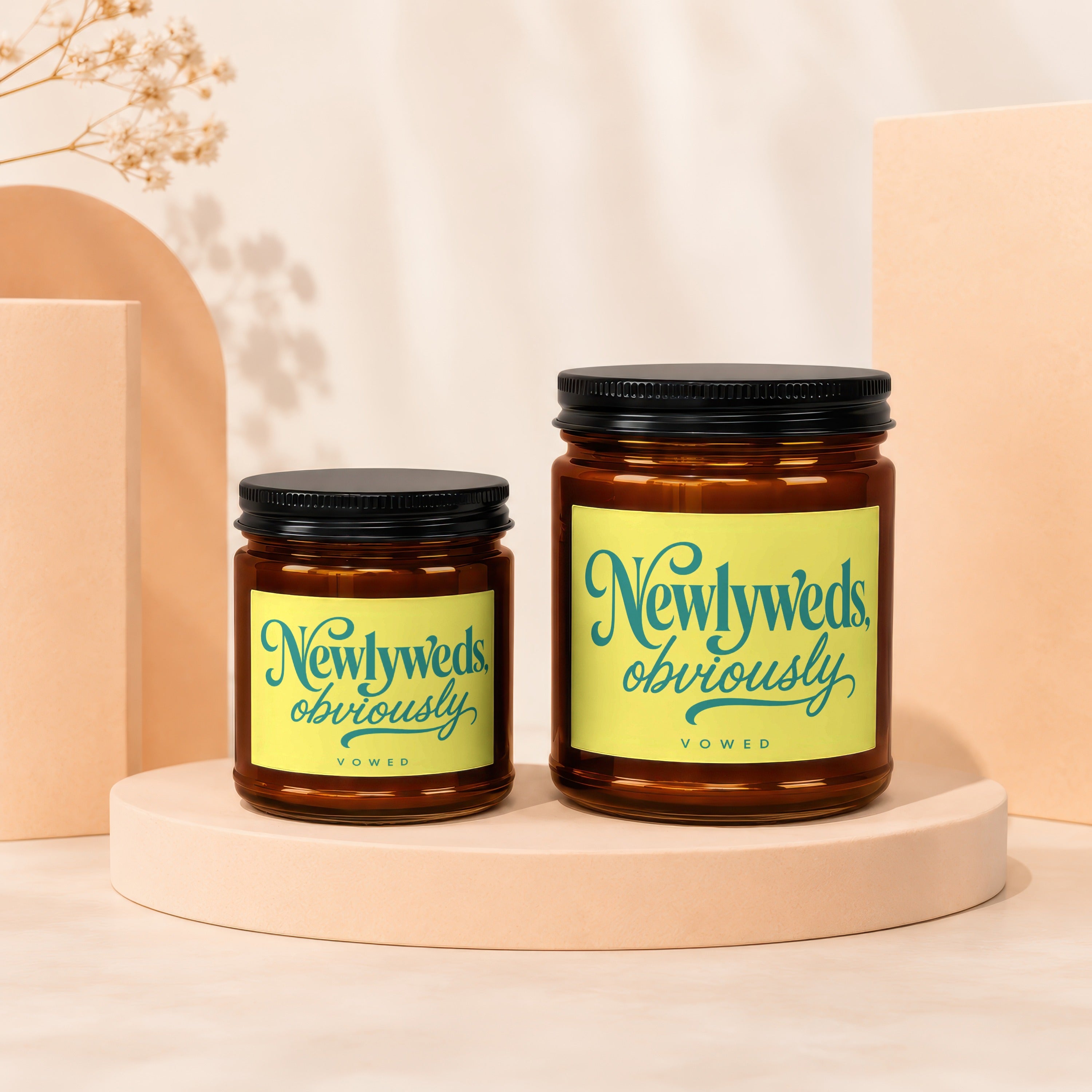 Two amber glass candles with black lids labeled "Newlyweds, obviously"
