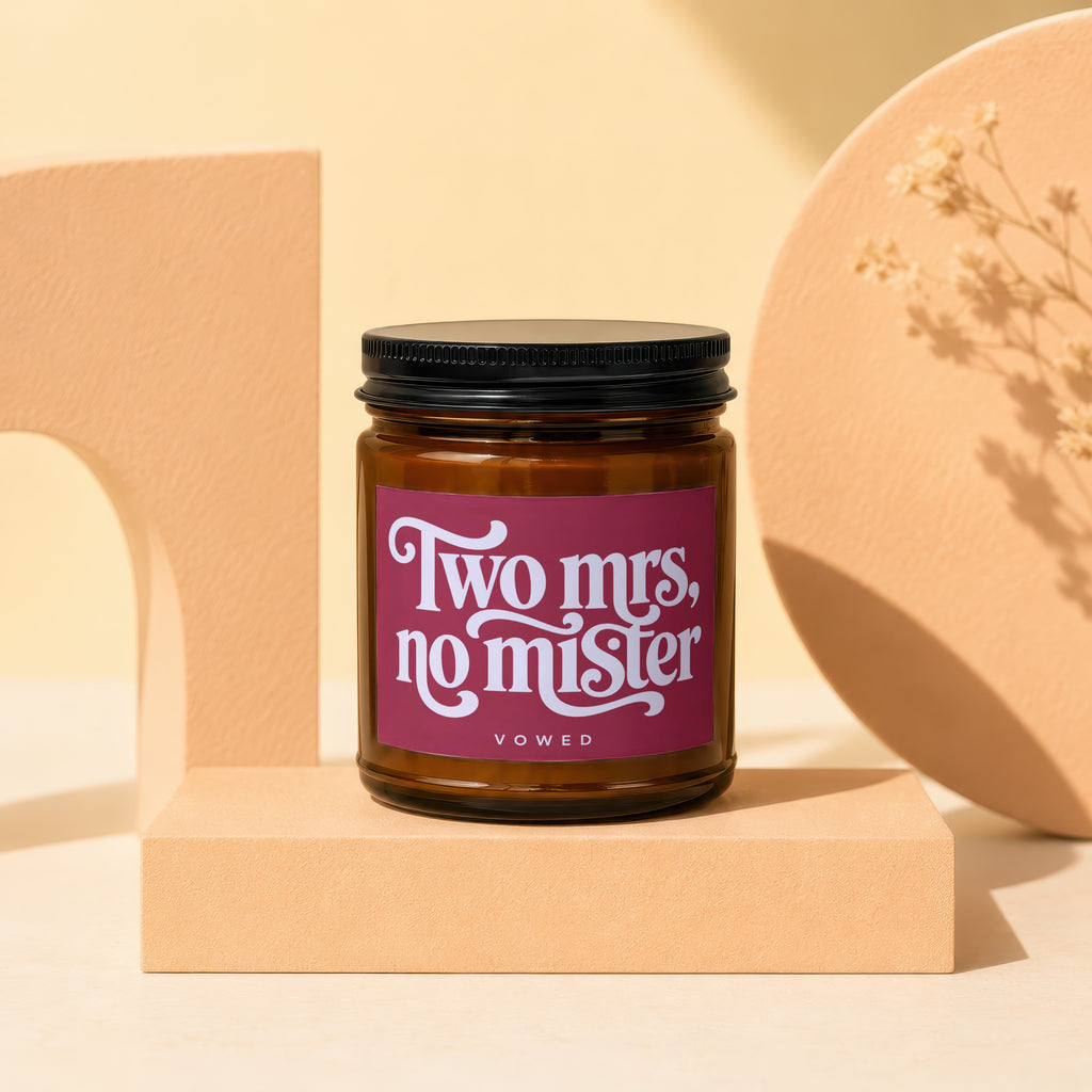 Amber glass candle with maroon label reading "Two mrs, no mister" and "vowed."