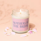 Lit candle in glass jar with "MOTHER OF THE BRIDE" text on pink label.