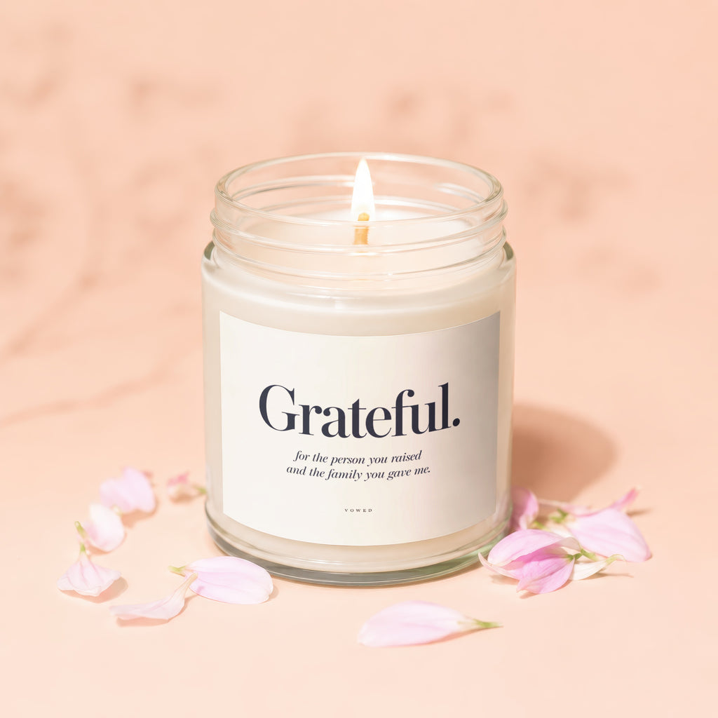 Candle with "Grateful." text, surrounded by pink petals on a peach background.