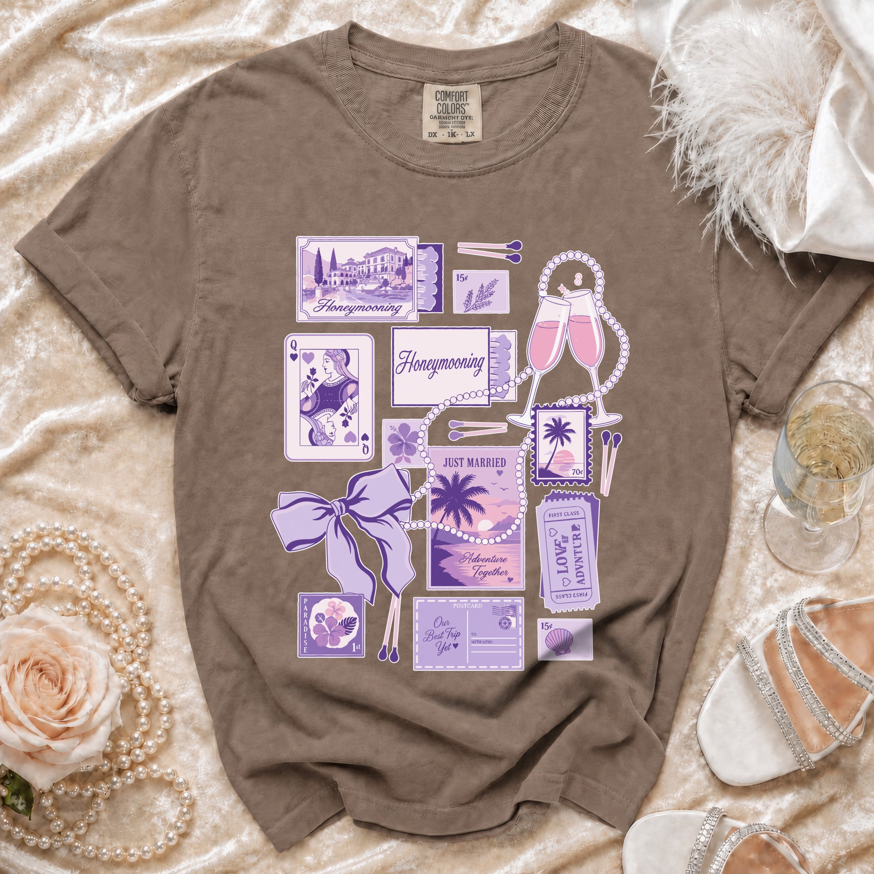 Brown t-shirt with purple honeymoon themed graphics, including tickets, stamps, and postcards.