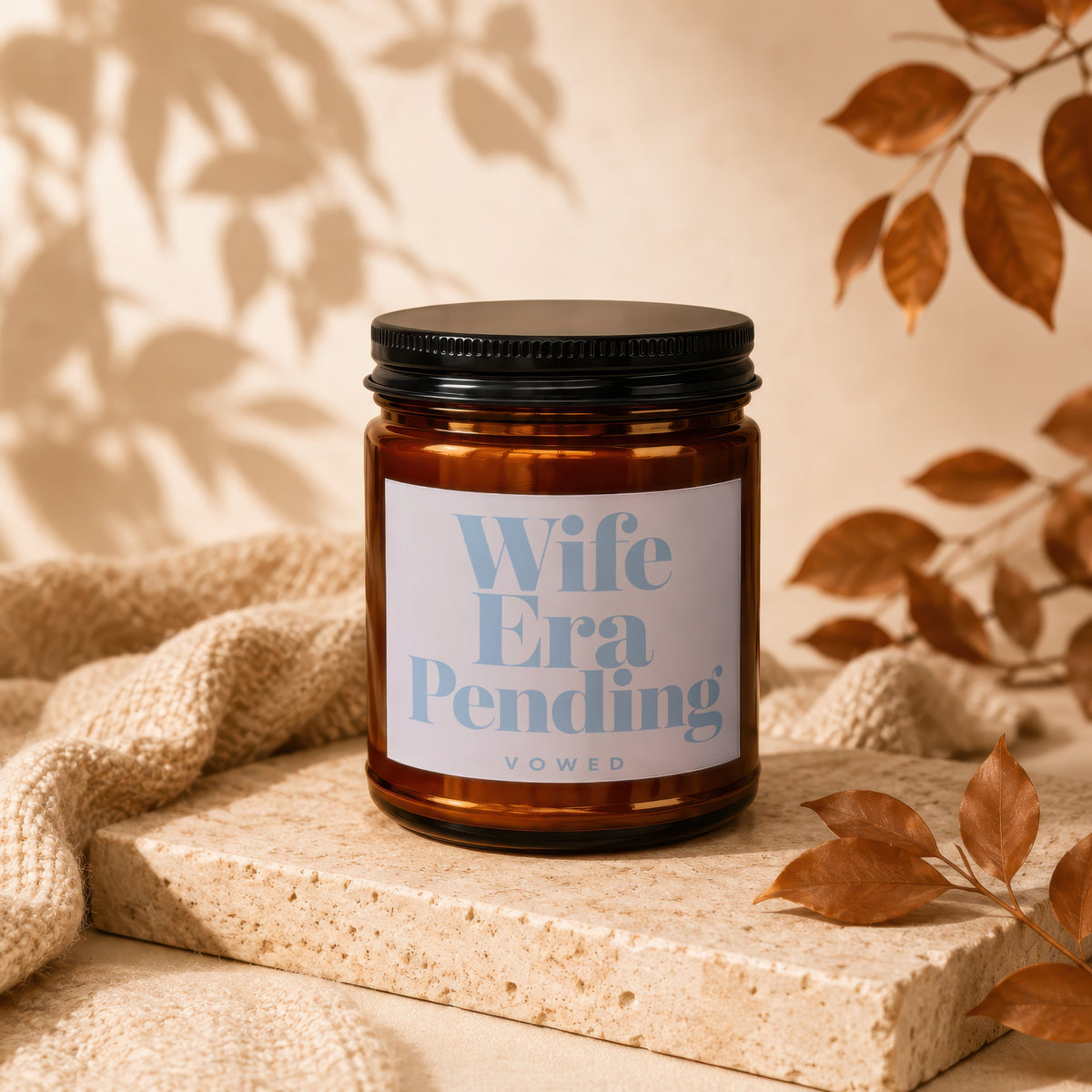 Hand-poured Vowed soy candle in an amber jar on a knit throw