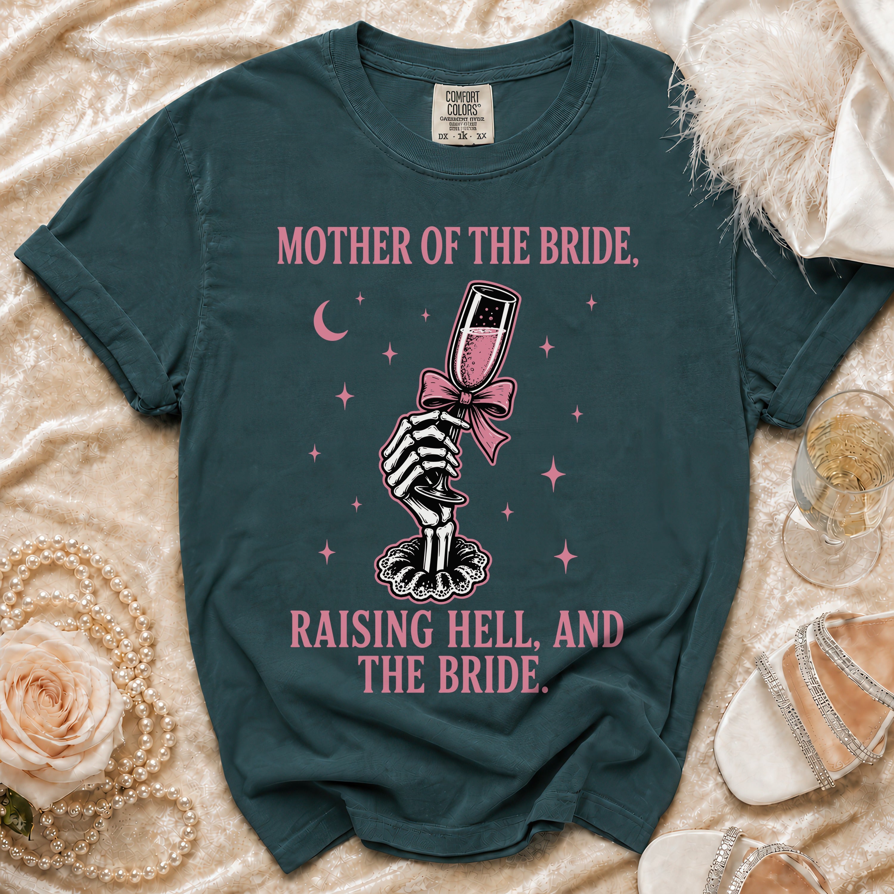 Dark teal t-shirt with "Mother of the Bride, Raising Hell, and the Bride" text and skeleton graphic.