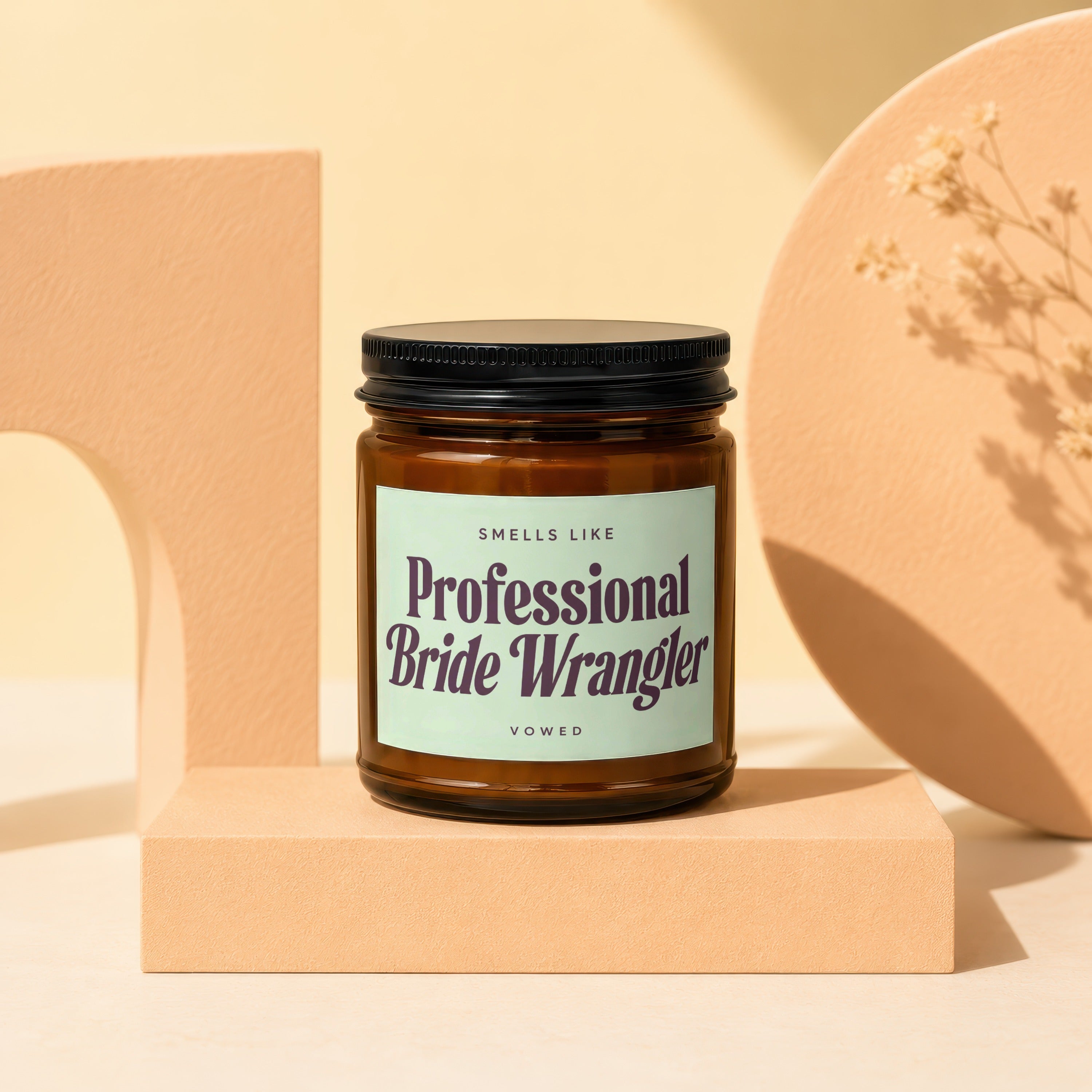 Brown glass candle with "Professional Bride Wrangler" text on a light green label.