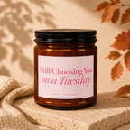 Amber jar candle with pink label reading "Still Choosing You on a Tuesday".