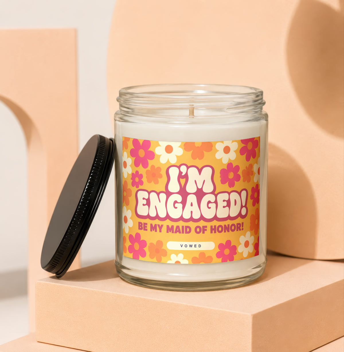 "I'm Engaged! Be My Maid of Honor!" candle with a floral label and black lid.