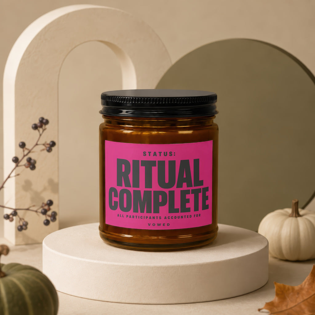 Amber jar candle with pink label reading "Status: RITUAL COMPLETE"