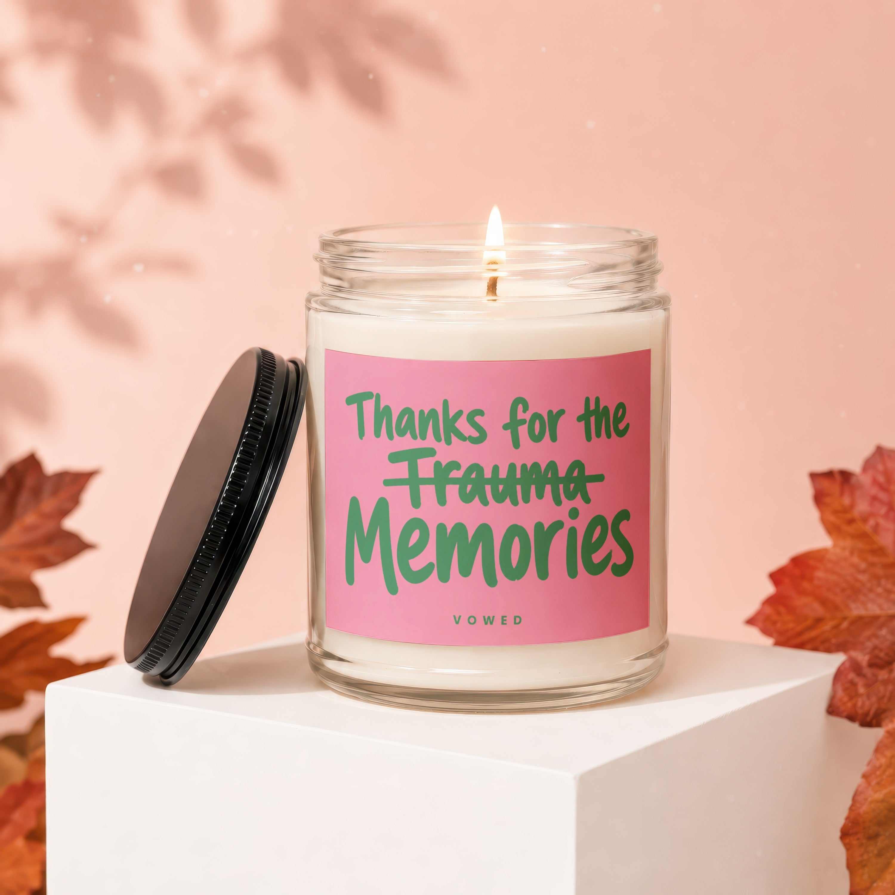Lit candle with pink label that reads "Thanks for the Trauma Memories"